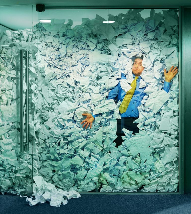 Mann hinter Glaswand mit viel Papier, zum Glück gibt es jetzt digitale Signaturen