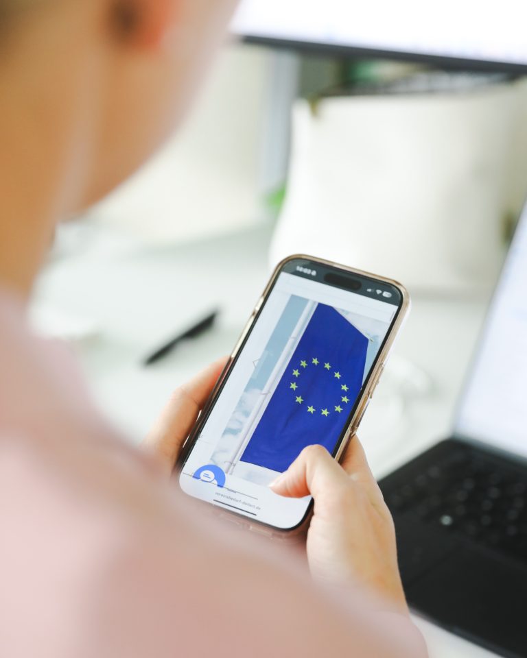 Frau am Handy mit Digital Wallet, auf dem Handy ist die Fahne der EU zu sehen
