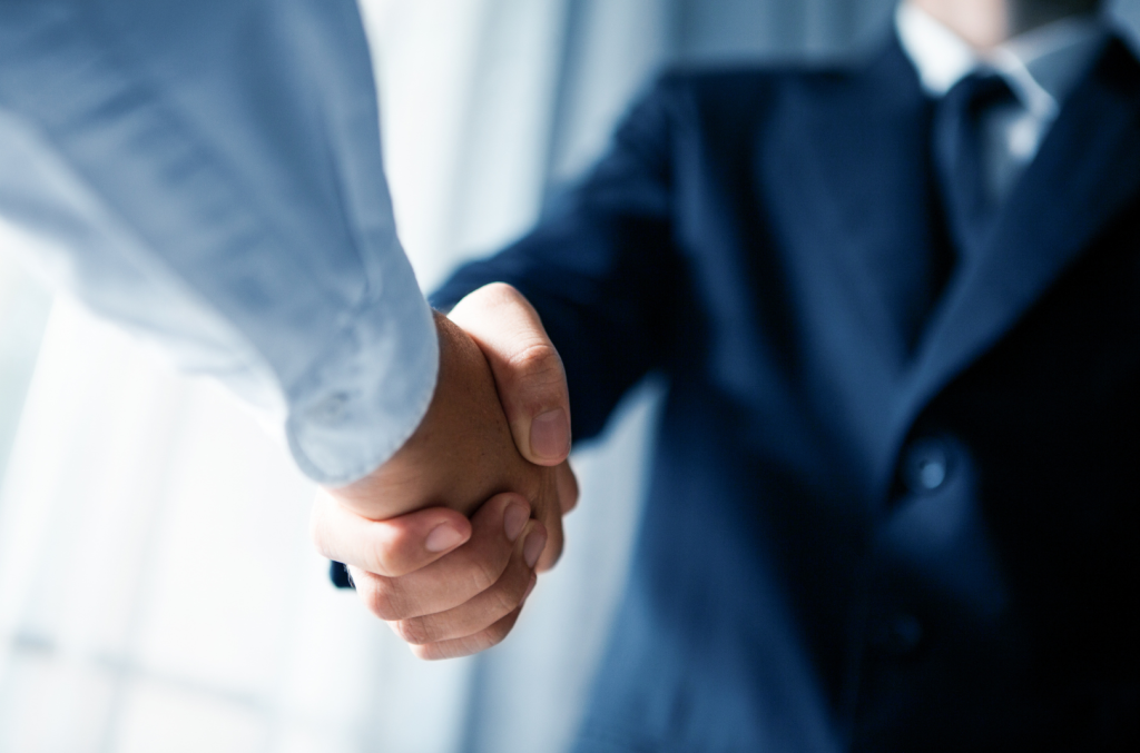 Zwei Männer in Business Kleidung schütteln sich die Hände Vertrauensdienste